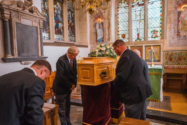 Alex Jones Funeral Directors - People bowing their heads in respect during a religious funeral service at a church